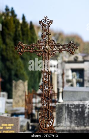 Ein altes rostiges katholisches Kreuz auf einem Friedhof in Frankreich. Stockfoto