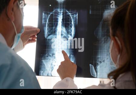 Junge Ärztin mit leitendem Arzt prüft eine Röntgenaufnahme. Konzept der Zusammenarbeit zwischen jungen Ärzten und erfahrenen Ärzten. Stockfoto