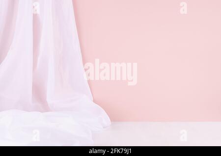 Abstrakte, minimalistische Szene oder Einrichtung mit hellrosa Wänden, weißem Seidenvorhang und weißem Holztisch. Hintergrund für die Anzeige, Stockfoto
