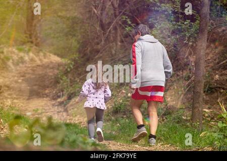 Enkelin läuft mit ihrem Großvater, um ihm zu helfen, wieder in Form zu kommen. Läuft bei Sonnenuntergang. Stockfoto