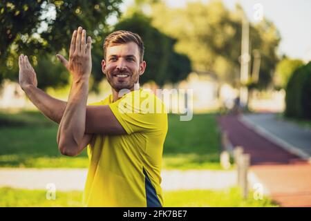 Der junge Mann trainiert draußen. Er dehnt seinen Körper und wärmt sich zum Joggen auf. Stockfoto