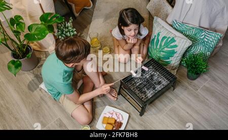 Draufsicht auf Brüder, die zu Hause kampieren und auf Sumpfgebieten toasten Stockfoto