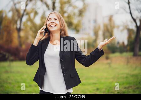 Außenportrait einer glücklichen Geschäftsfrau, die am Telefon spricht. Stockfoto