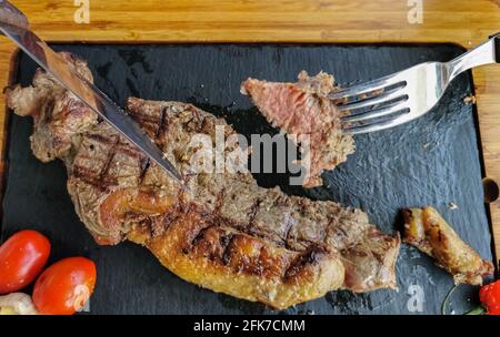 Detailansicht einer geschnittenen Portion Rindfleisch auf Gabel, Kartoffelpüree und Bohnen Reis, gegrilltes Rindersteak mit großem Aspekt als Hintergrund... Stockfoto