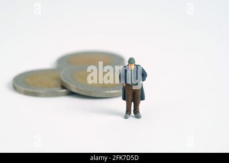 Armer Mann mit Münzgeld übrig. Miniatur winzigen Menschen Spielzeug Fotografie. Isoliert auf weißem Hintergrund. Stockfoto