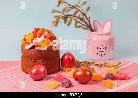 Ostern. Osterkuchen mit Eiern und Hasenohren auf blauem Hintergrund. Ostern. Vase mit blühenden Ästen. Stockfoto