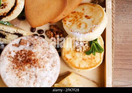 Apfel- und Mohn-Strudel, Kekse und duftender Zimtkaffee auf einem rustikalen Holztablett. Draufsicht, Nahaufnahme. Stockfoto