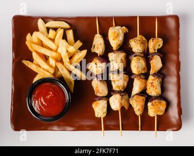 Hähnchenspieße. Zartes Hähnchenfilet, gegrillt mit süßen Zwiebelringen, garniert mit pommes Frites und zart Stockfoto