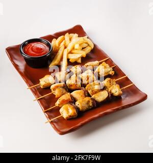 Hähnchenspieße. Zartes Hähnchenfilet, gegrillt mit süßen Zwiebelringen, garniert mit pommes frites Stockfoto