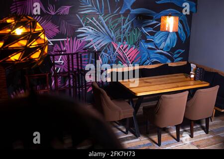 Tisch in einem Café mit Neonzeichnungen an den Wänden. Stockfoto