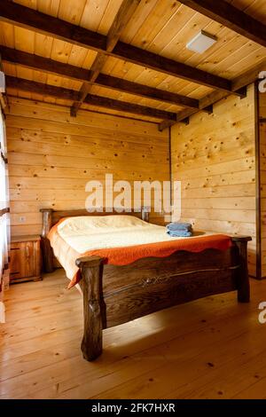 Helles, minimalistisches, helles Schlafzimmer mit Holzmöbeln und Wänden in einer neu gebauten Berghütte. Stockfoto