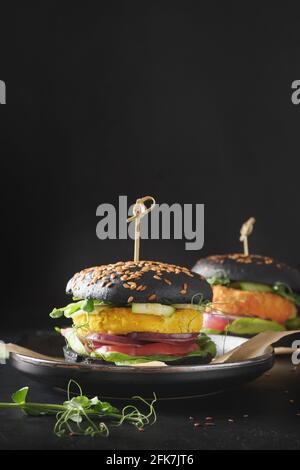 Vegane schwarze Burger von Gemüsefleischbällchen Pflanzen Fleisch auf schwarzem Hintergrund. Nahaufnahme. Vertikale Ausrichtung. Stockfoto