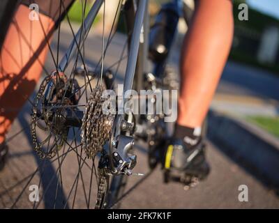 Nahaufnahme der hinteren Fahrradkassette mit Kette und Bremsscheibe. Radfahrer fahren Rennrad an einem sonnigen Tag Stockfoto