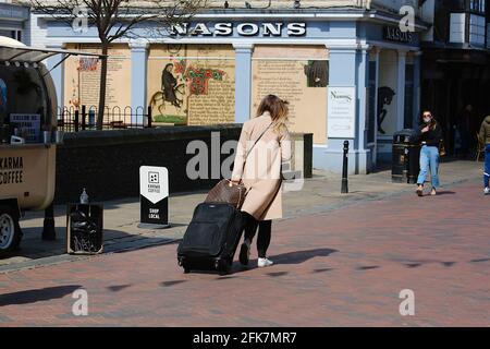 Canterbury, Kent, Großbritannien. 29. April 2021. Die Stadt Canterbury in Kent gewinnt langsam wieder etwas an Normalität, da viele Menschen auf der Hauptstraße herumlaufen und das angenehme Wetter genießen. Eine Frau, die Gepäck durch die Hauptstraße zieht. Foto-Kredit: Paul Lawrenson /Alamy Live Nachrichten Stockfoto