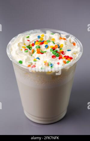 Weißer Milchshake mit bunten Kugeln auf grauem Hintergrund. Stockfoto