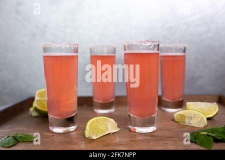 Vier rosafarbene Cocktails mit Limetten auf einem Holzständer. Stockfoto
