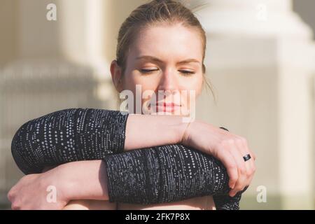 Portrait von schönen jungen blonden Haaren Mädchen auf die Kamera mit Gesicht in den Händen genießen das Leben, Sonnenbaden, träumen und entspannen im Sommer Stockfoto