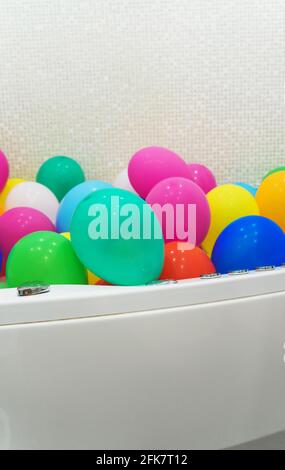 Die Badewanne ist mit bunten Luftballons gefüllt. Stockfoto