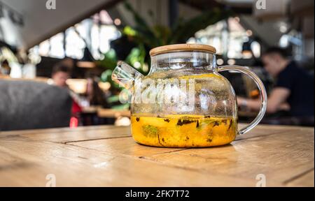 Sanddorntee in Glas Teekannen mit Minze und Gewürzen auf Holztisch im Café. Traditionelles herbstliches Heißgetränk. Selektiver Fokus. Stockfoto