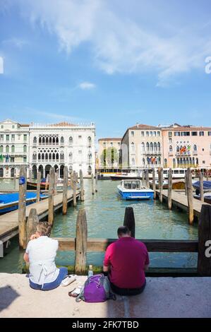 VENEDIG, ITALIEN - 01. Mai 2016: Nicht identifizierte Menschen ruhen an einem Kanal im Stadtzentrum an einem sonnigen Tag Stockfoto