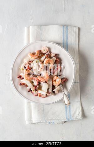 Aperitif mit frischen Garnelen und Krake-Salat auf zartem Hintergrund. Draufsicht. Speicherplatz kopieren. Stockfoto