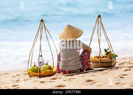 Vietnamesische Frau, die am Strand von Mui Ne Früchte verkauft. Vietnam. MUI Ne weißer Sandstrand in Vietnam. Stockfoto