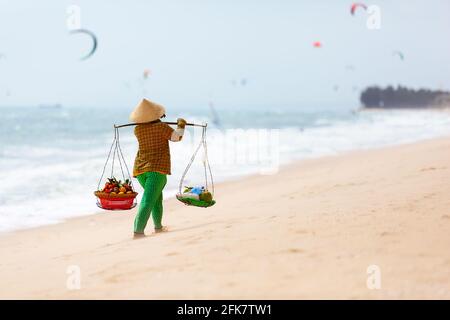 Vietnamesische Frau, die am Strand von Mui Ne Früchte verkauft. Vietnam. MUI Ne weißer Sandstrand in Vietnam. Stockfoto