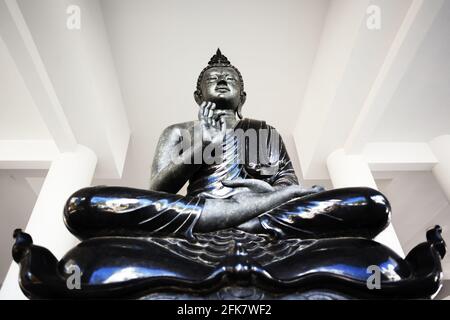 Eine schwarze Buddha-Statue in einem weißen Tempel in Thailand Stockfoto