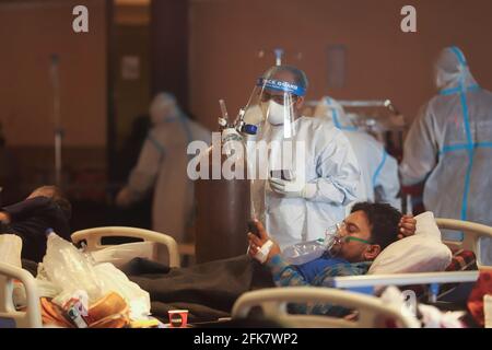Delhi, Indien. April 2021. Ein Mitarbeiter des Gesundheitswesens, der einen persönlichen Schutzanzug (PSA) trägt, betreut einen Covid19-Patienten auf der Isolationsstation in Neu-Delhi. Ein Bankettsaal, der vorübergehend zu einer Covid19-Station für Coronavirus-Patienten umgebaut wurde. Indien hat die höchste eintägige Spitze bei einer Coronavirus-Infektion verzeichnet. Kredit: SOPA Images Limited/Alamy Live Nachrichten Stockfoto