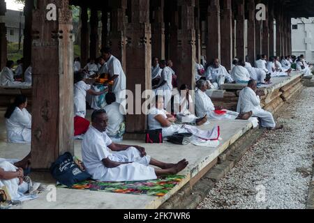 Kandy, Sri Lanka: Einige weiß gekleidete Gläubige sitzen im Gebet oder ruhen sich im Tempel der heiligen Zahnreliquie aus (Sri Dalada Maligawa) Stockfoto