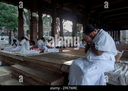 Kandy, Sri Lanka: Einige weiß gekleidete Gläubige sitzen im Gebet oder ruhen sich im Tempel der heiligen Zahnreliquie aus (Sri Dalada Maligawa) Stockfoto