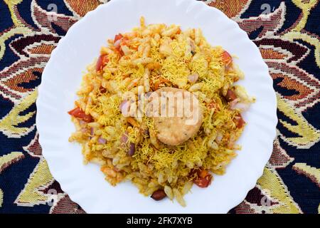 Bhelpuri, indisches beliebtes Straßenessen aus Puffreis und sev. Indische Teezeit-Snacks werden auf einem Teller auf dem Tisch serviert. Besondere berühmte Chaat Artikel von I Stockfoto