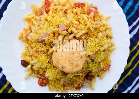 Bhelpuri, indisches beliebtes Straßenessen aus Puffreis und sev. Indische Teezeit-Snacks werden auf einem Teller auf dem Tisch serviert. Besondere berühmte Chaat Artikel von I Stockfoto