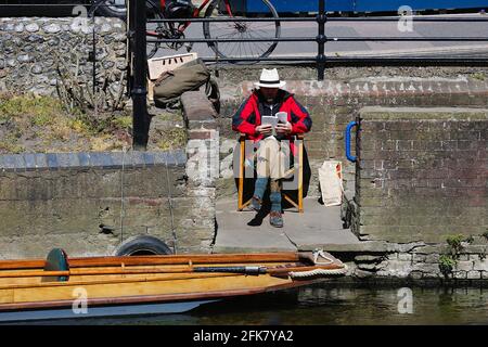 Canterbury, Kent, Großbritannien. 29. April 2021. Die Stadt Canterbury in Kent gewinnt langsam wieder etwas an Normalität, da viele Menschen auf der Hauptstraße herumlaufen und das angenehme Wetter genießen. Ein Puntsman liest ein Buch, das auf die Arbeit wartet. Foto-Kredit: Paul Lawrenson /Alamy Live Nachrichten Stockfoto