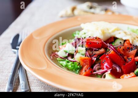 Gemüsegericht, Salat mit Pfeffer, Tomaten, italienische Mischung, frischer Salat, Gebratener Käse. Gesunde Ernährung. Salat mit Tomaten, Gurken, Käse und Zwiebeln Stockfoto