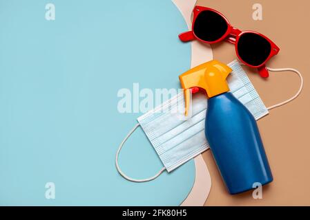 Schützende OP-Maske mit Sonnenbrille und Plastikflasche Sonnenschutzmittel Mit Kopierraum auf buntem Hintergrund.Sommerkonzept mit covid-19 Stockfoto