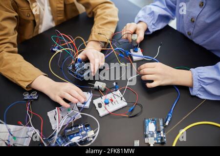 Draufsicht Nahaufnahme von nicht erkennbaren Kindern, die Roboter bauen und mit elektrischen Schaltungen experimentieren, im Ingenieursunterricht in der Schule, Kopierraum Stockfoto