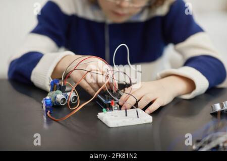 Nahaufnahme eines nicht erkennbaren Kindes, das mit elektrischen Schaltungen experimentiert, während Bauen von Robotern während des Ingenieursunterschurs in der Schule Stockfoto