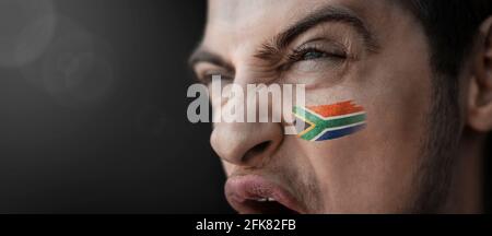 Ein schreiender Mann mit dem Bild Südafrikas Nationalflagge auf seinem Gesicht Stockfoto