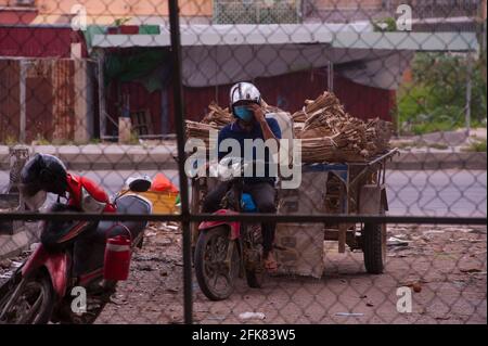 Phnom Penh, Kambodscha. 29. April 2021. Aufgrund der jüngsten Ausbrüche von COVID - 19 in Bekleidungsfabriken und -Märkten hat die kambodschanische Regierung eine Sperre auferlegt. Die Regierung hat Stueng Meanchey jetzt als „Rote Zone“ bezeichnet, alles wurde geschlossen, einschließlich Lebensmittelgeschäfte. Kambodschaner in den „Roten Zonen“ haben fast keinen Zugang zu Nahrungsmitteln und dürfen nicht aus ihren Häusern. Hier kann ein Brennholz-Lieferer sein Holz nicht liefern, weil die Straße gesperrt ist. Viele Kambodschaner sind während der Coronavirus-Pandemie in Quarantäne auf ihren eigenen Straßen. Quelle: Kraig Lieb / Alamy Live News Stockfoto