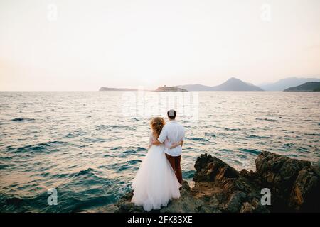 Braut und Bräutigam stehen umarmt auf den Felsen vorbei Das Meer und Blick in die Ferne Stockfoto