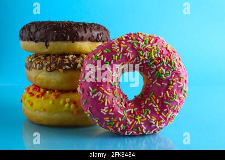 Ein Stillleben Food Donut berliner in einer rosa Glasur mit einem farbigen Ständer von Donuts auf einem blauen hellen Hintergrund . Stockfoto