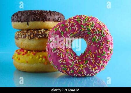 Ein Stillleben Food Donut berliner in einer rosa Glasur mit einem farbigen Ständer von Donuts auf einem blauen hellen Hintergrund . Stockfoto