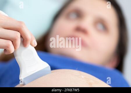 Nahaufnahme des Ultraschallaufnehmers am Bauch einer Schwangeren. Gynäkologie-Büro. Stockfoto