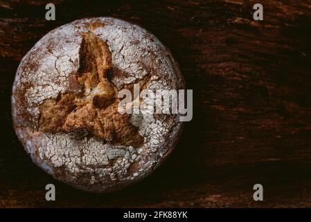 Knuspriger runder Laib gesundes Vollkornbrot auf dunklem Holztisch-Hintergrund mit weißem Mehl auf der Oberseite. Draufsicht auf Buchweizen selbstgebackenes Brot Stockfoto