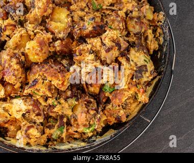 Blick von oben auf eine rustikale Pfanne mit Bratkartoffeln, Eiern und Speck auf einem dunklen Tisch Stockfoto