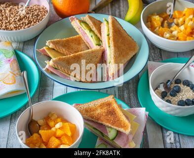 Stellen Sie den Frühstückstisch zu Hause mit Sandwiches, Obst und Müsli von oben auf Stockfoto