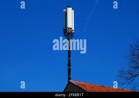 Ein Handy-Mast auf einem Hausdach in Frankfurt, mit Tauben. Stockfoto