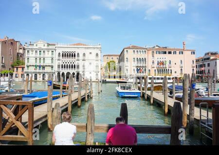 VENEDIG, ITALIEN - 01. Mai 2016: Nicht identifizierte Menschen ruhen an einem Kanal im Stadtzentrum an einem sonnigen Tag Stockfoto