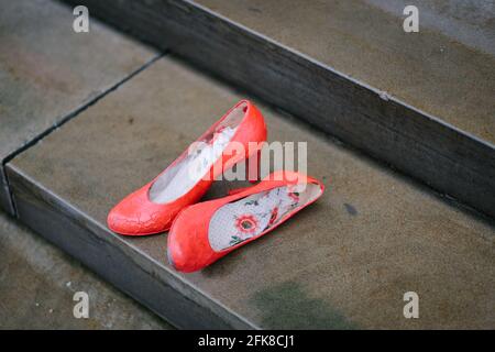 Hannover, Deutschland. April 2021. Rote Schuhe stehen vor dem niedersächsischen Parlament während der Kampagne „Rote Schuhe“ gegen den Austritt der Türkei aus der Istanbuler Konvention. Jedes Paar Schuhe steht für eine Frau, die durch Gewalt gestorben ist. Die Farbe Rot steht für das verschüttete Blut. Die Aktionsform geht auf die mexikanische Künstlerin Elina Chauvet zurück, die 2009 das Projekt 'Zapatos Rojos' ('Rote Schuhe') ins Leben gerufen hat und bereits Aktionen mit roten Schuhen in verschiedenen Ländern durchgeführt hat, um verschwundene, misshandelte, vergewaltigte und ermordete Frauen zu gedenken. Quelle: Ole Spata/dpa/Alamy Live News Stockfoto